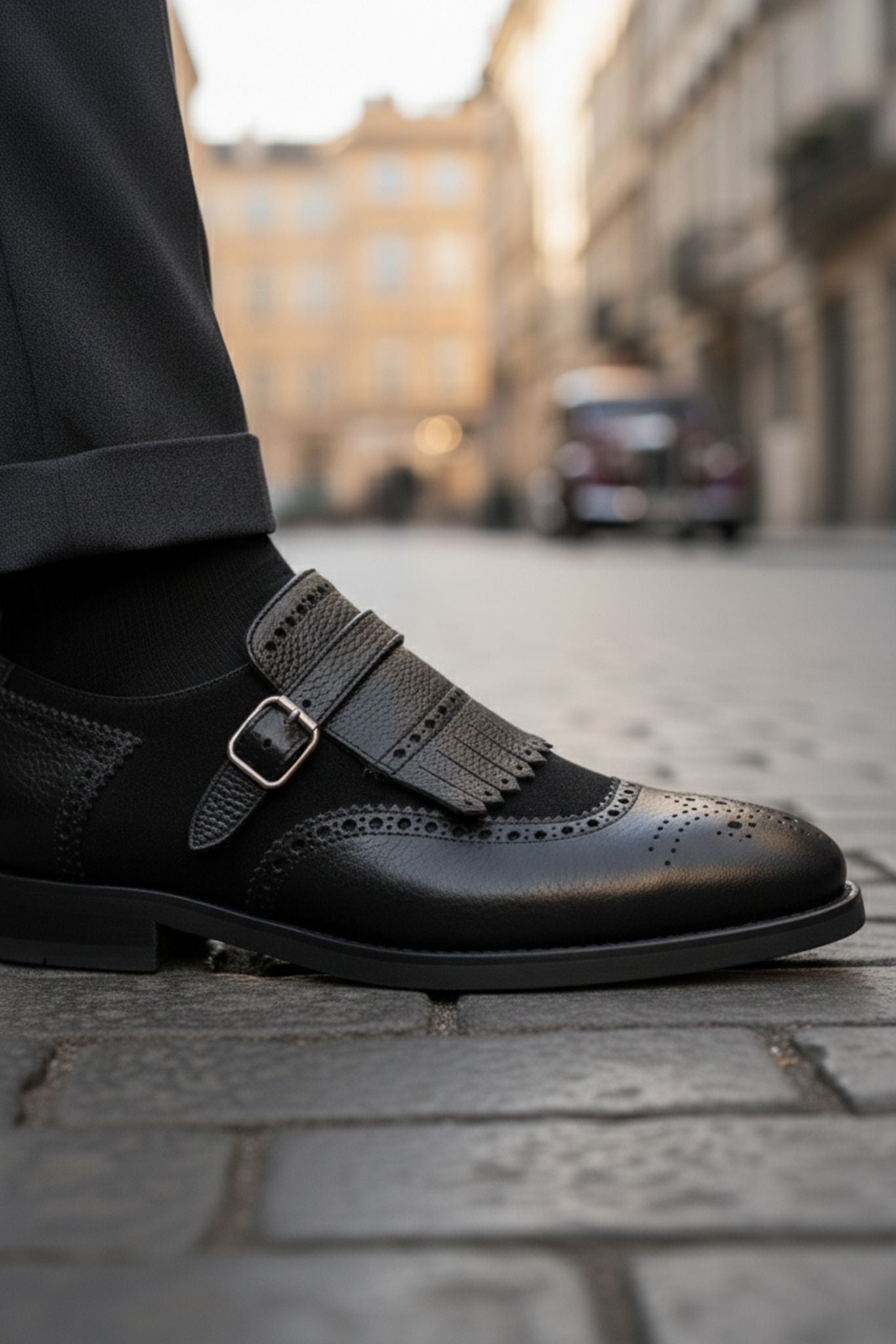 Black leather shoe with gray strap on a city street