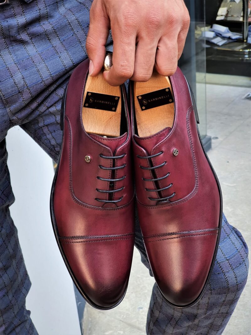 Man in blue plaid suit holding Bordeaux Crest Luxe Cap-Toe Oxfords, showcasing stylish pairing.