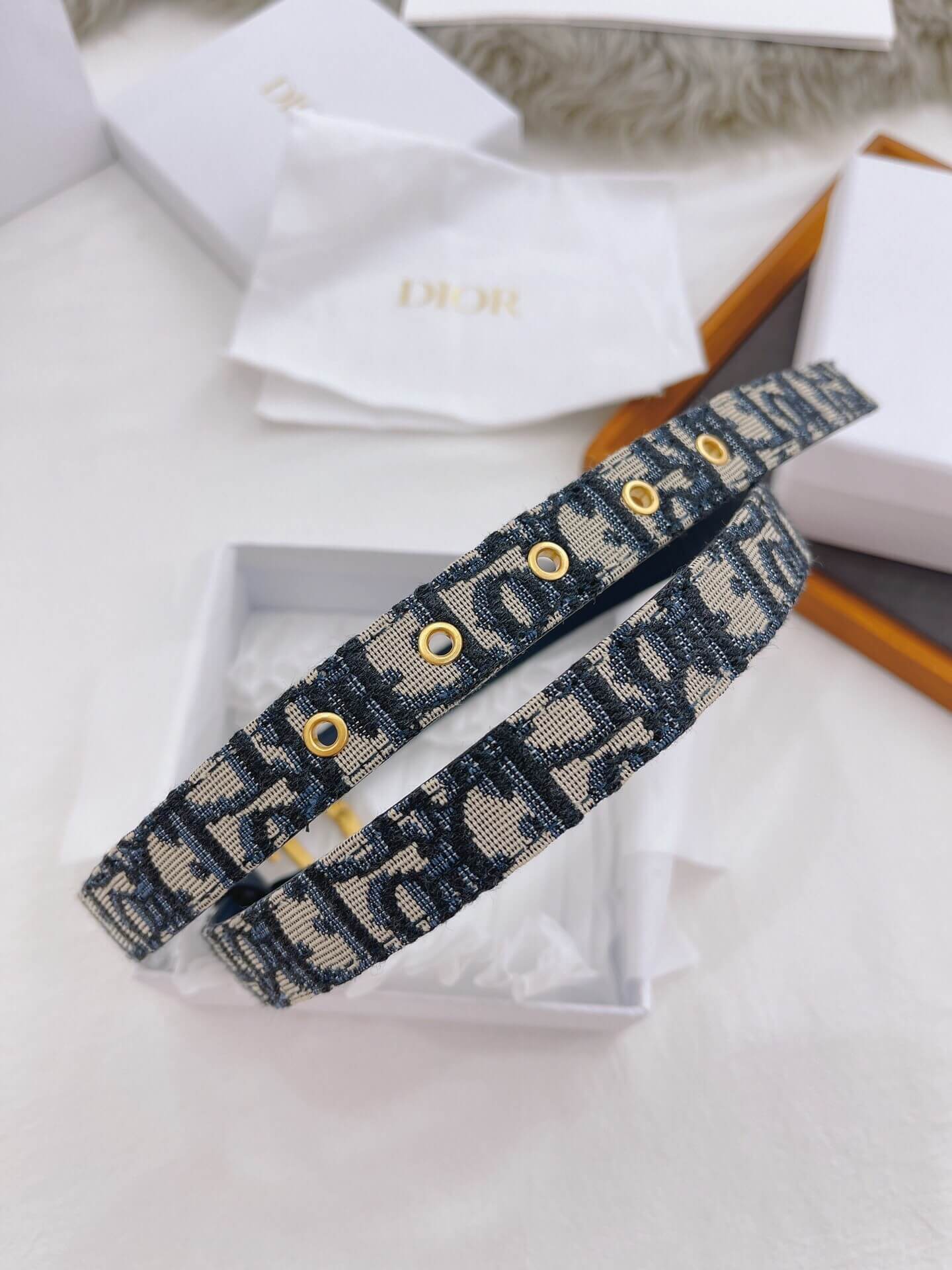 Blue patterned belt with gold buttons on a white surface