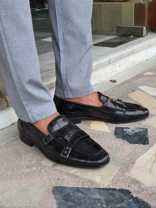Black Crocodile-Embossed Double Monk Strap Shoes – pair worn by a man in light grey trousers, showcasing the bold crocodile pattern and sophisticated double monk strap design