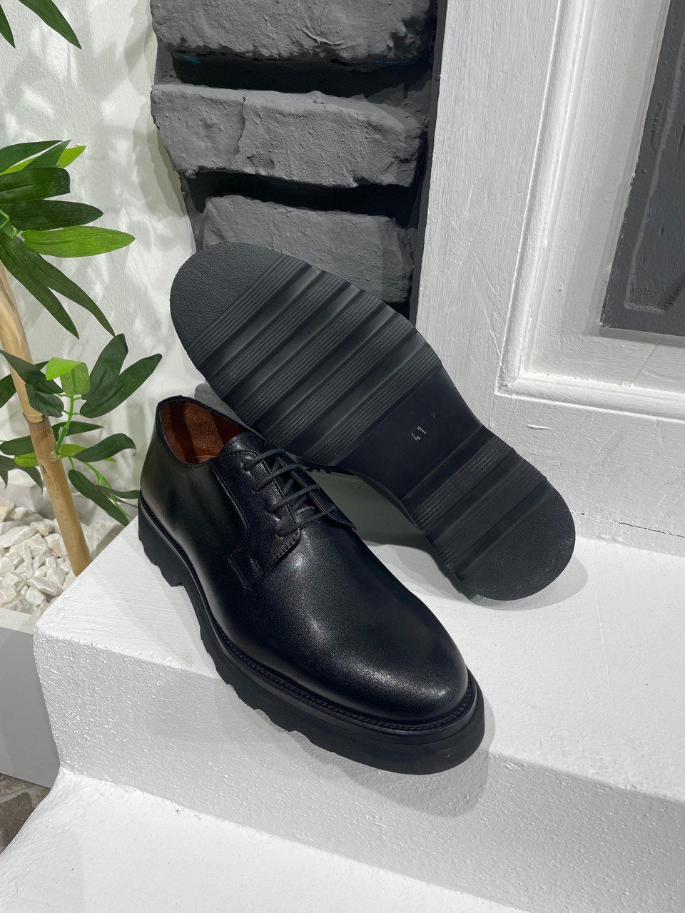 Classic Black Leather Derby Shoes – chunky sole and smooth leather finish, with one shoe upright and one showing the sole, for modern versatility.