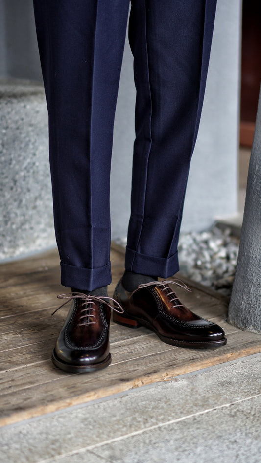Side view of handcrafted brown Oxford brogue shoes worn with trousers on wooden deck – timeless men’s dress style