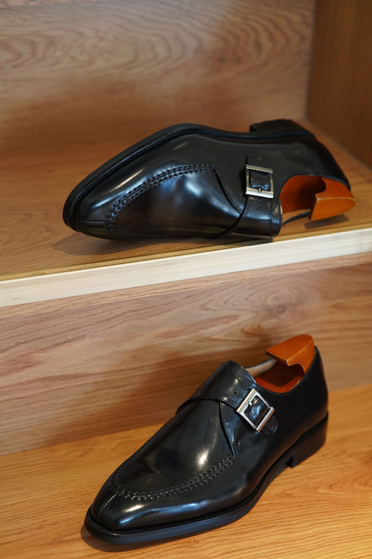 Handcrafted Black Single Monk Strap Dress Shoes – pair with shoe trees, angled view on wooden steps, highlighting polished black leather and sleek design.