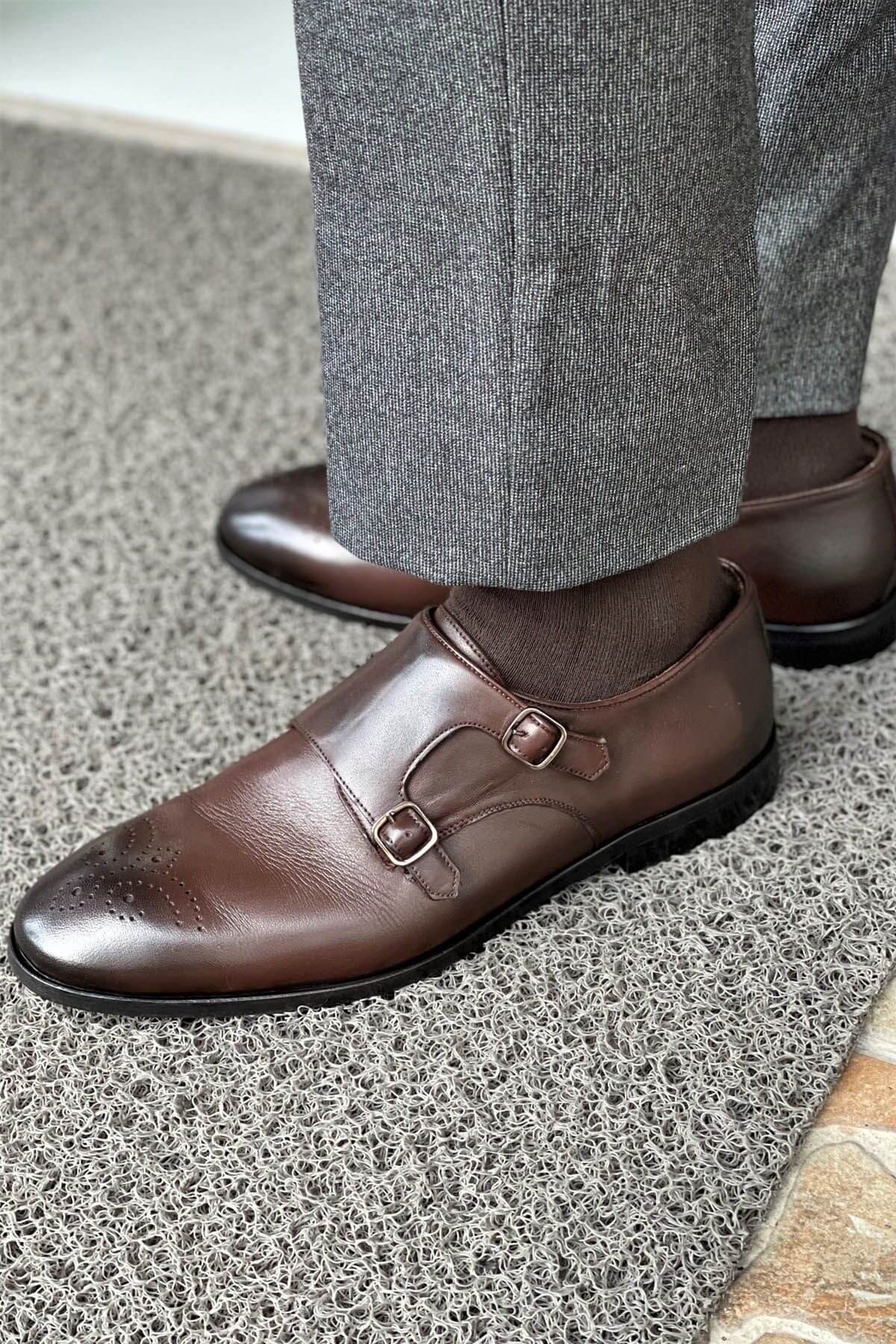 Brown leather shoes with a buckle on a textured floor