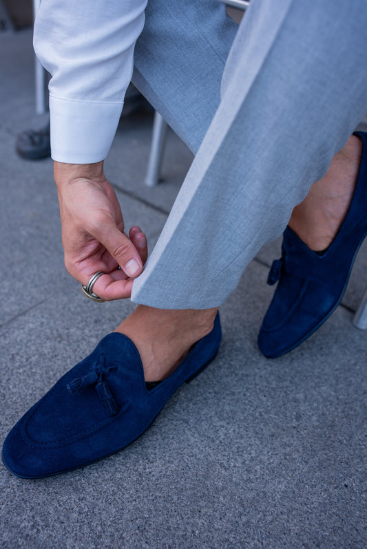 Handmade Navy Blue Suede Loafers for Versatile Style – man adjusting cuffed light grey trousers, showcasing a sleek silhouette and comfortable fit.