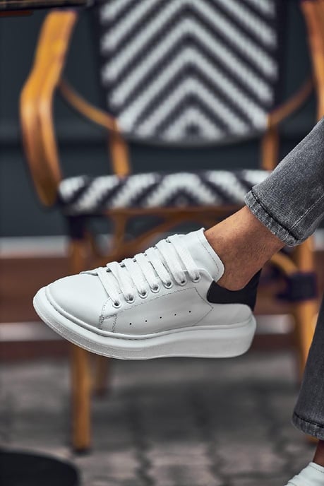 Handmade White Leather Sneakers - Luxury Comfort for Every Occasion – worn by a man, with one foot lifted, highlighting the exaggerated sole and a sleek silhouette for a fashion-forward look.