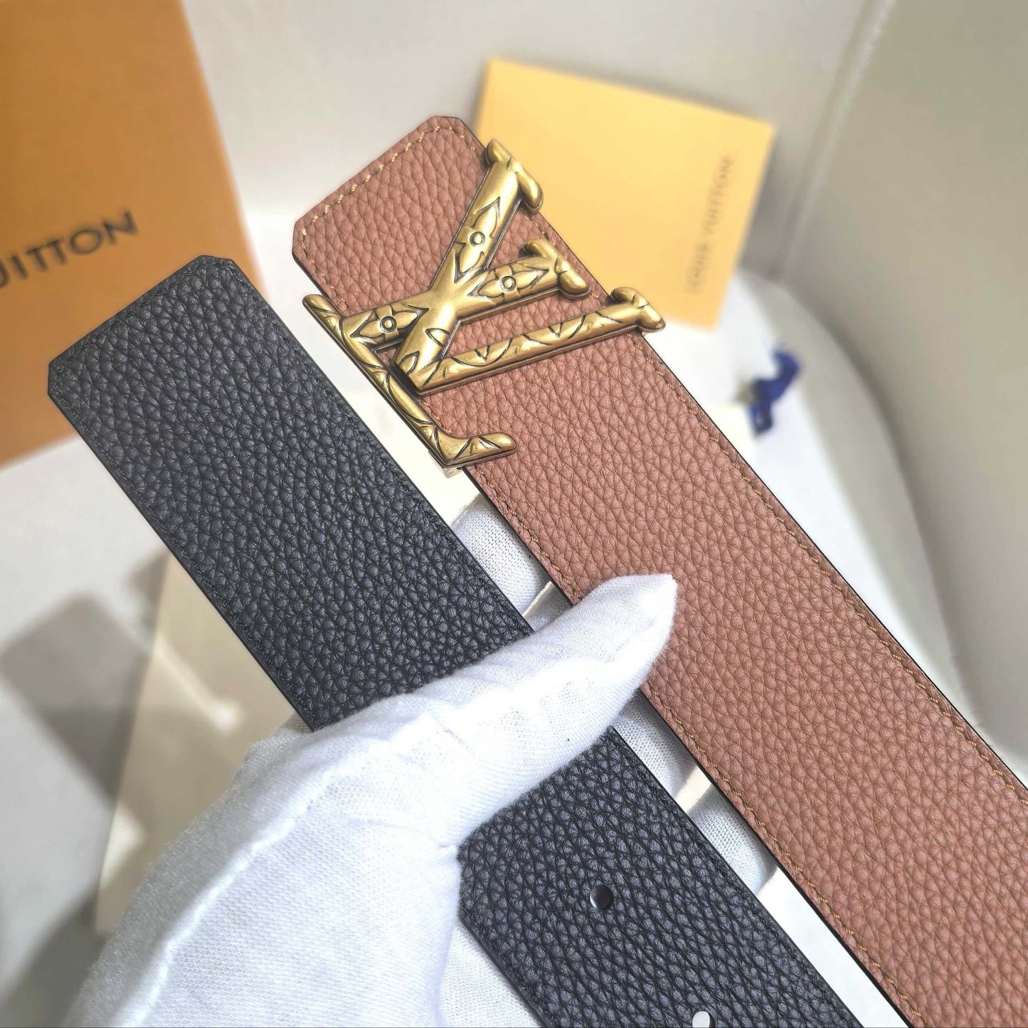 Two belts, one black and one brown with gold buckle, on a white surface.