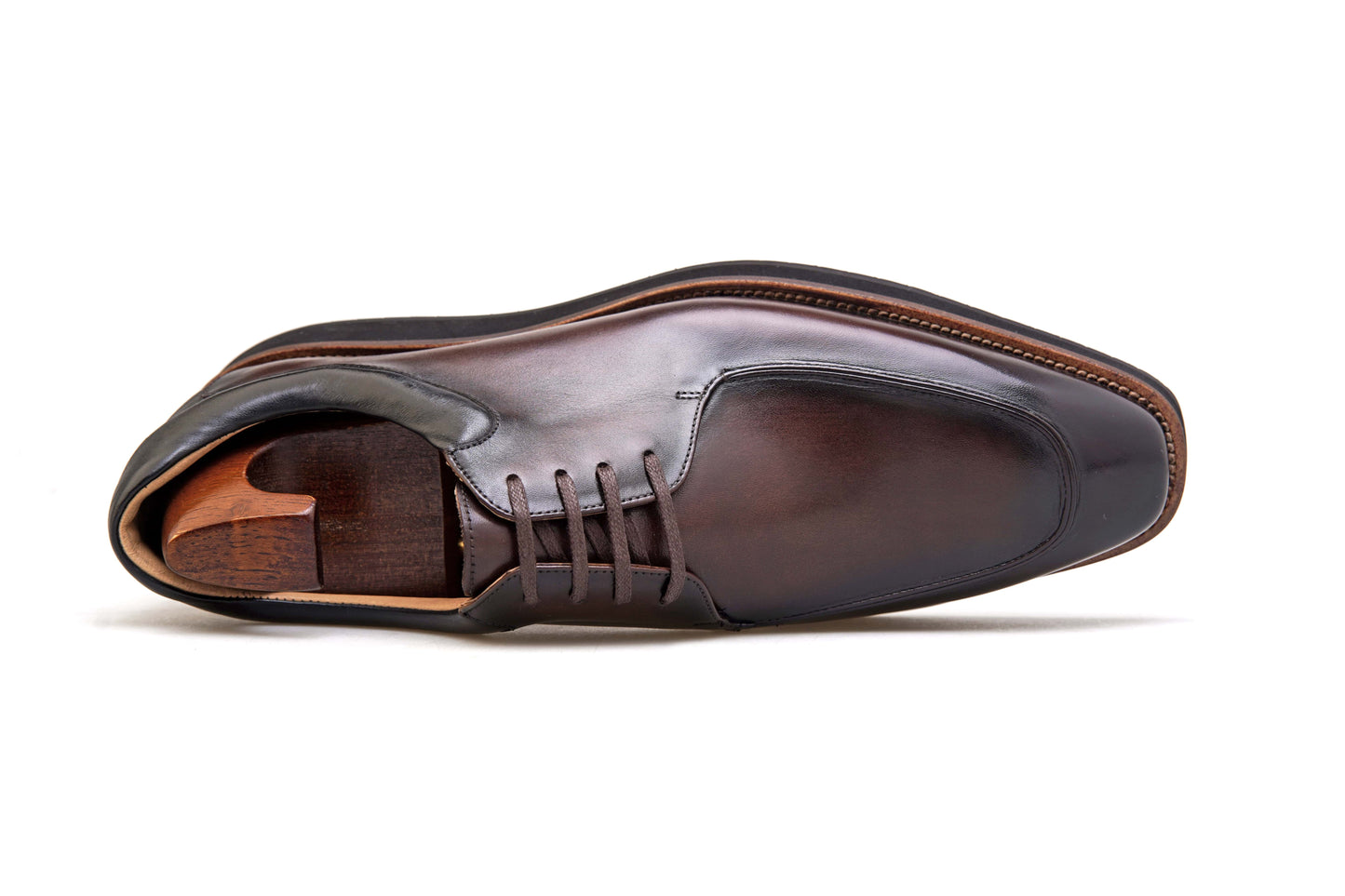 Pair of Modern Apron-Toe Derby Shoes in high-shine brown leather with black lug soles and shoe trees, angled view.