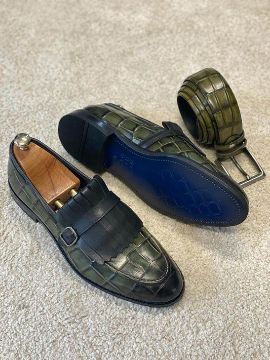 Olive green croc-embossed loafers with black fringe kiltie and belt on cream carpet