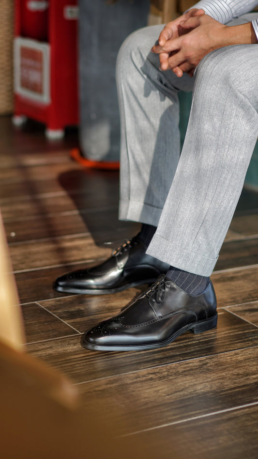 Sophisticated Black Wingtip Derby Shoes – premium leather, pair on a woven surface with intricate brogue detailing and shoe trees.