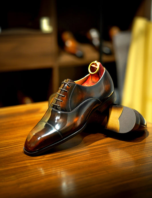 Brown-grain leather Balmoral oxford dress shoe – close‑up side view with blurred shelf background