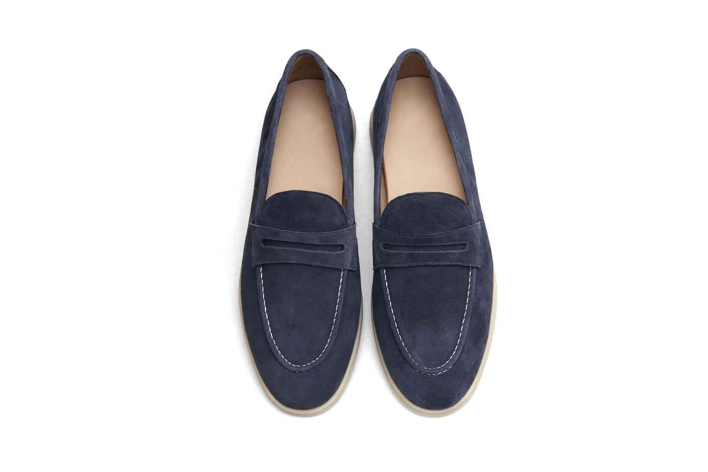 Single navy blue suede penny loafer on white background, vamp and strap detail