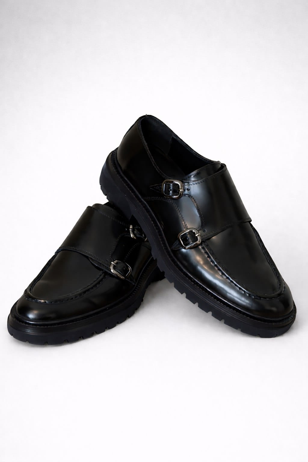 Pair of black leather shoes with buckles on a white background