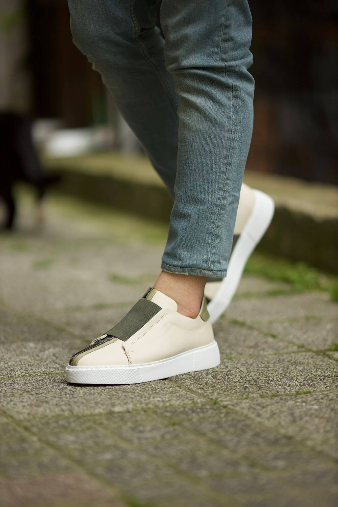 Vince Beige & Green Slip-On Sneakers - Sophisticated Comfort for Every Occasion – worn by a man in light blue jeans, walking on a paved ground, highlighting the stylish design and all-day comfort.