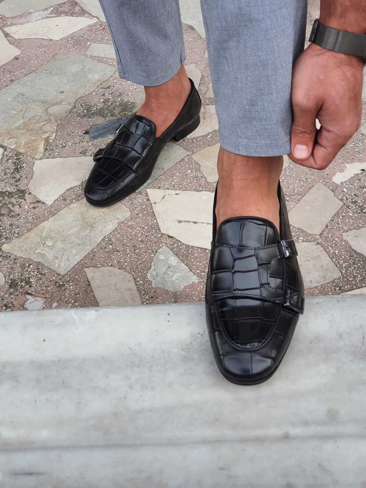 Black Crocodile-Embossed Double Monk Strap Shoes – pair worn by a man in light grey trousers, showcasing the bold pattern and modern elegance from above.
