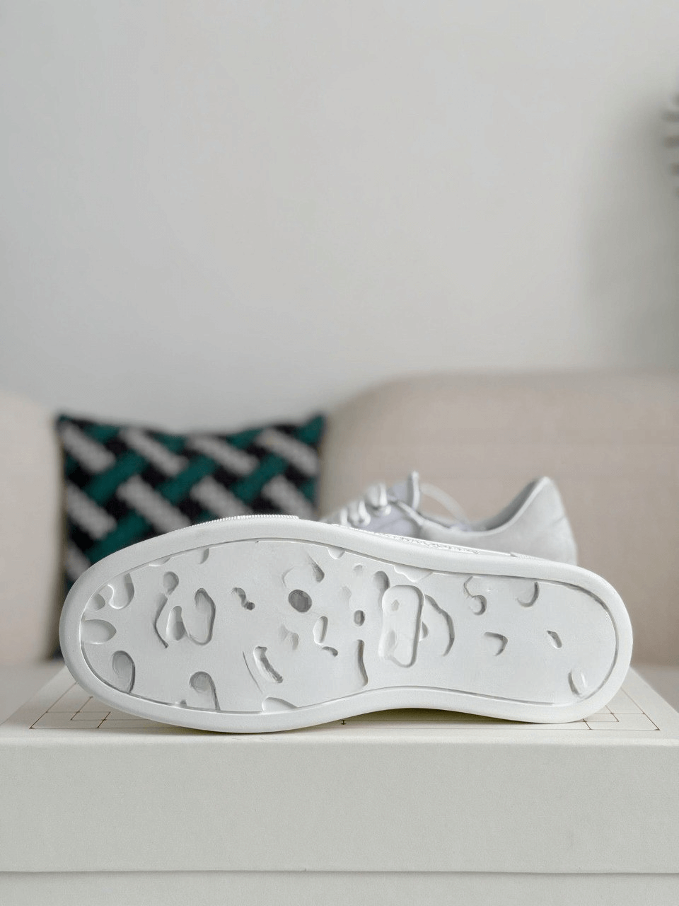White sneaker with unique sole design on a light surface