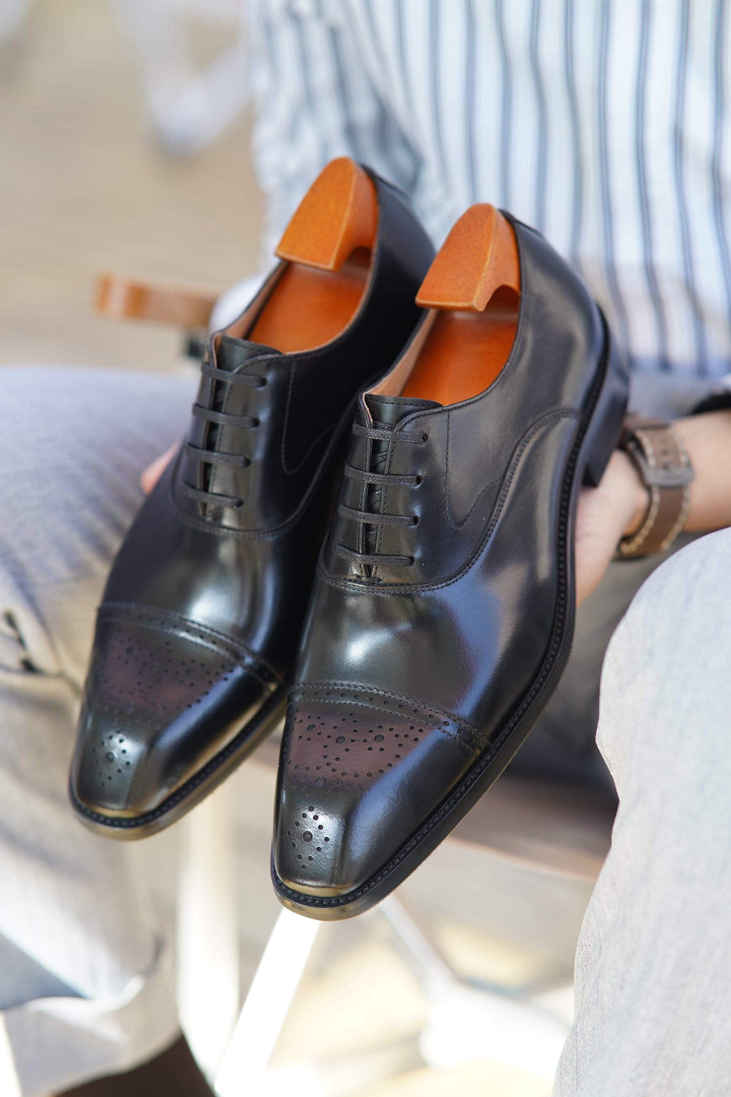 Men's black leather Oxford shoes with a cap toe, brogue detailing, and closed lacing.