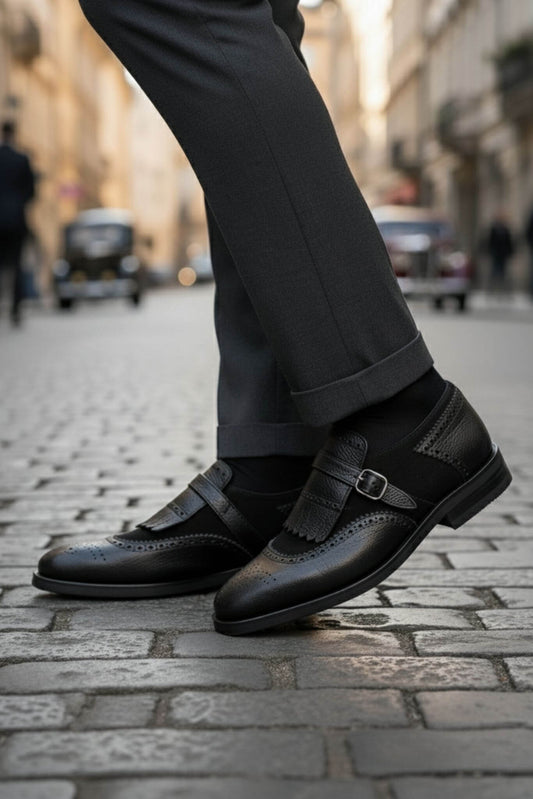 Black shoes with a buckle worn on a cobblestone street.