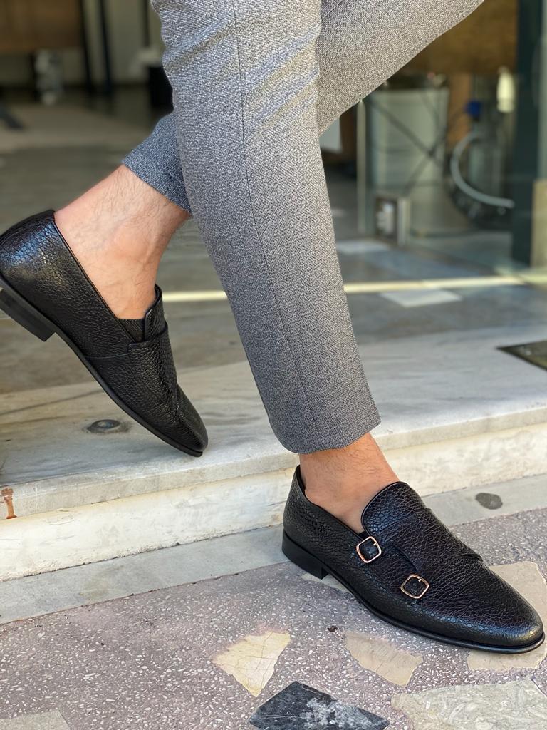 Black Grained Leather Double Monk Strap Shoes – worn by a man in grey trousers, stepping on patterned ground, highlighting textured leather and secure buckles.