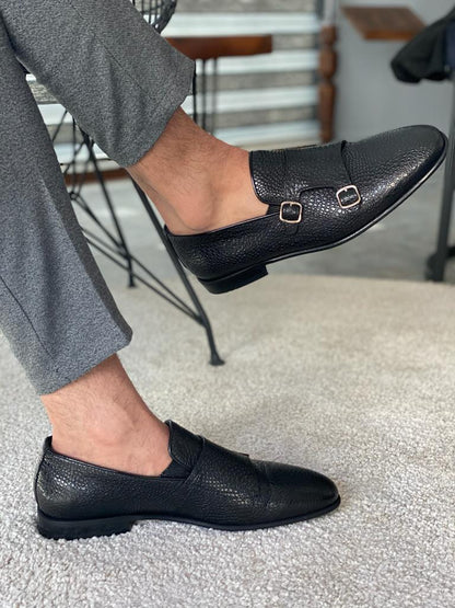 Black Grained Leather Double Monk Strap Shoes – worn by a man in grey trousers, showcasing textured leather and double buckle design on a rug.