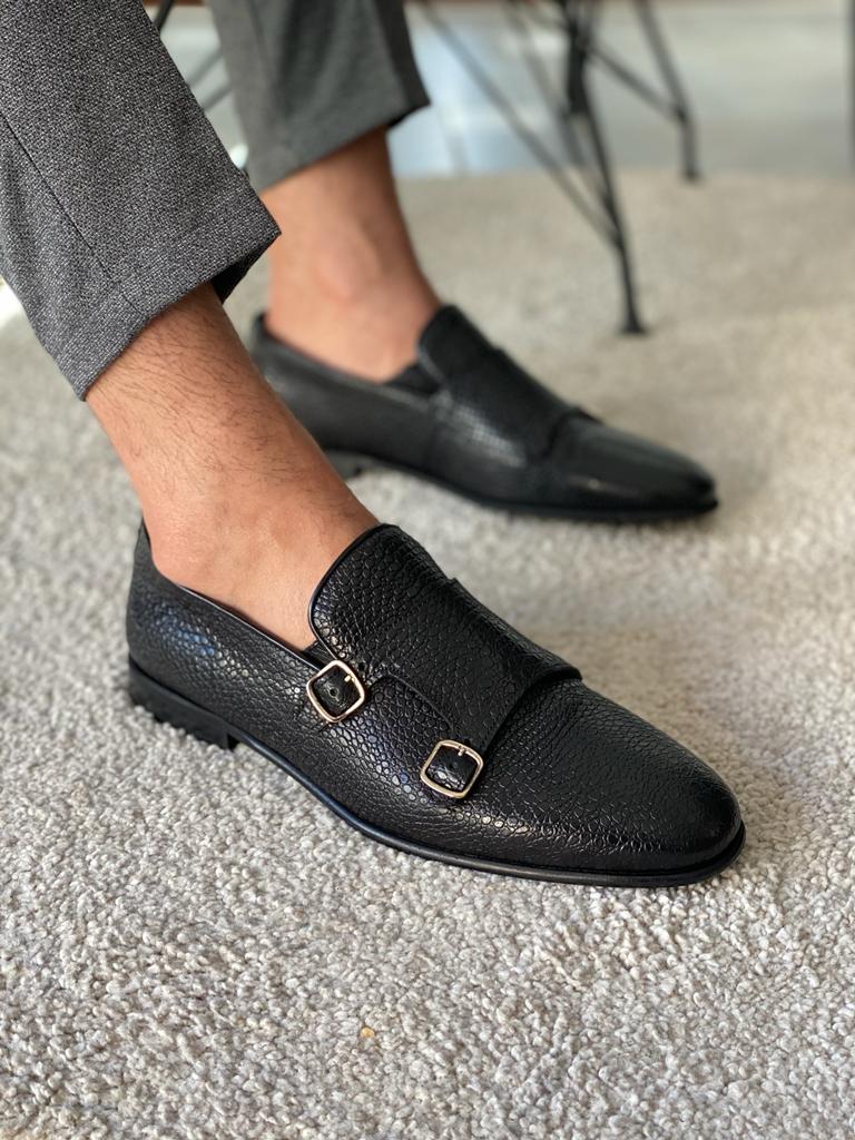 Black Grained Leather Double Monk Strap Shoes – worn by a man in grey trousers, close-up on a rug, emphasizing elegant double buckles and textured finish.