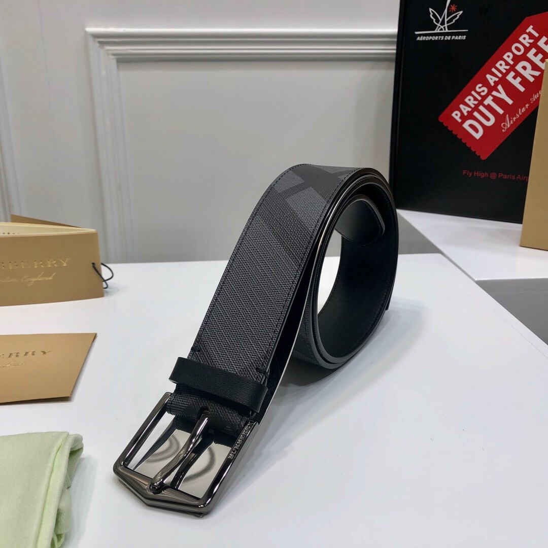 Black belt with silver buckle on a white surface with boxes in the background