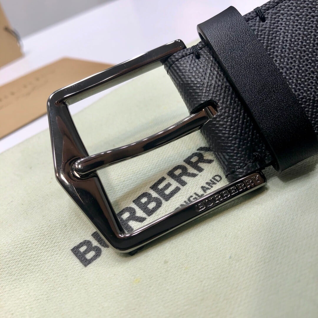 Black Burberry belt with a shiny buckle on a branded surface
