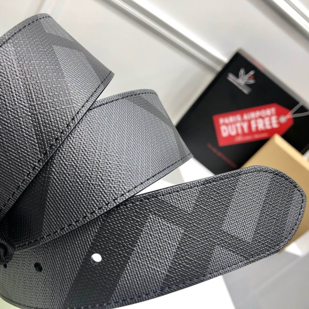 Gray belt with a checkered pattern on a white surface, with Duty Free label in the background.