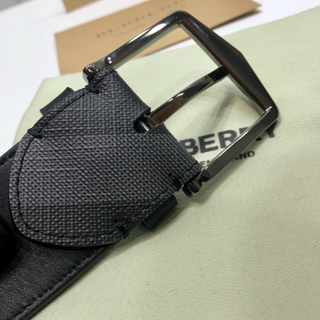 Black belt with a shiny buckle on a light green surface