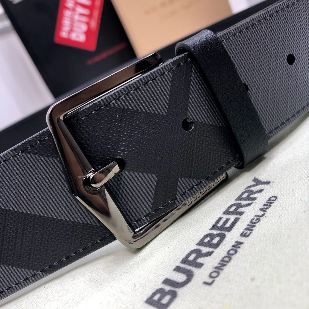 Black Burberry belt with a silver buckle on a Burberry branded surface.