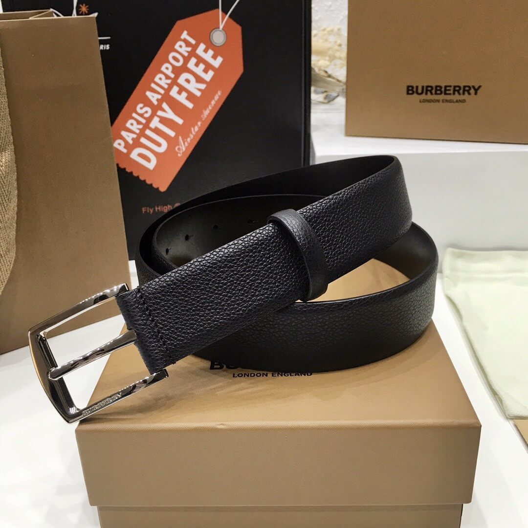 Black leather belt on a Burberry box with 'Paris Airport Duty Free' tag in the background.