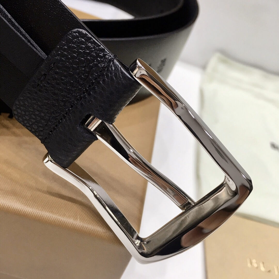 Close-up of a black leather belt with a silver buckle on a blurred background