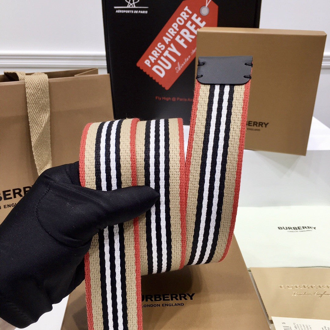 Striped belt held by a gloved hand with Burberry branding in the background
