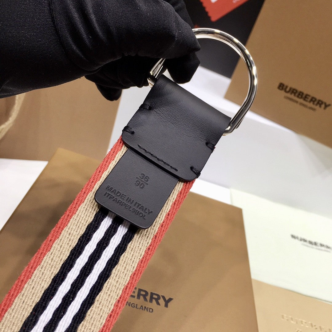 Burberry belt with a black buckle held by a gloved hand, with Burberry branding in the background.