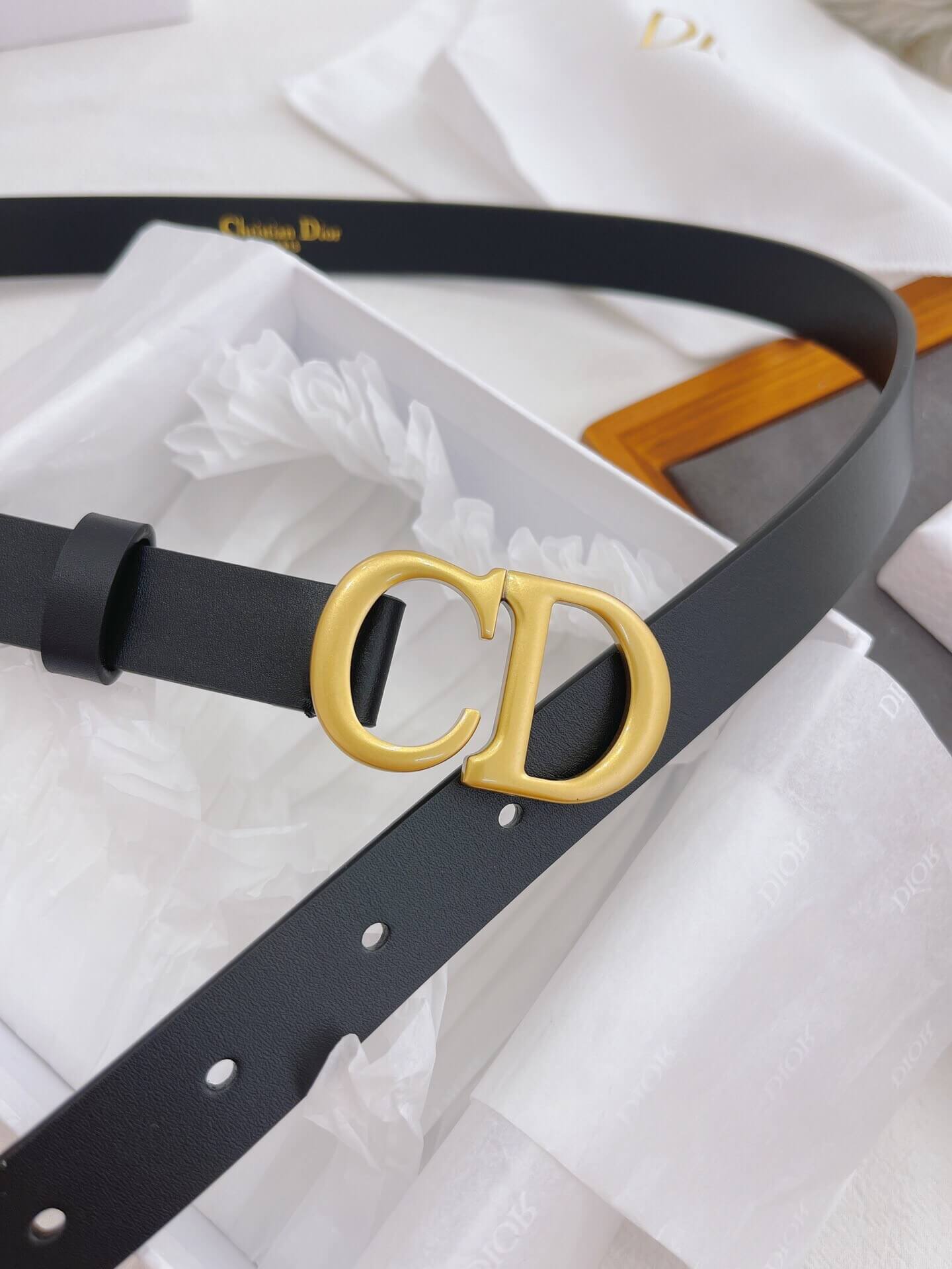 Black belt with gold Dior buckle on a white background
