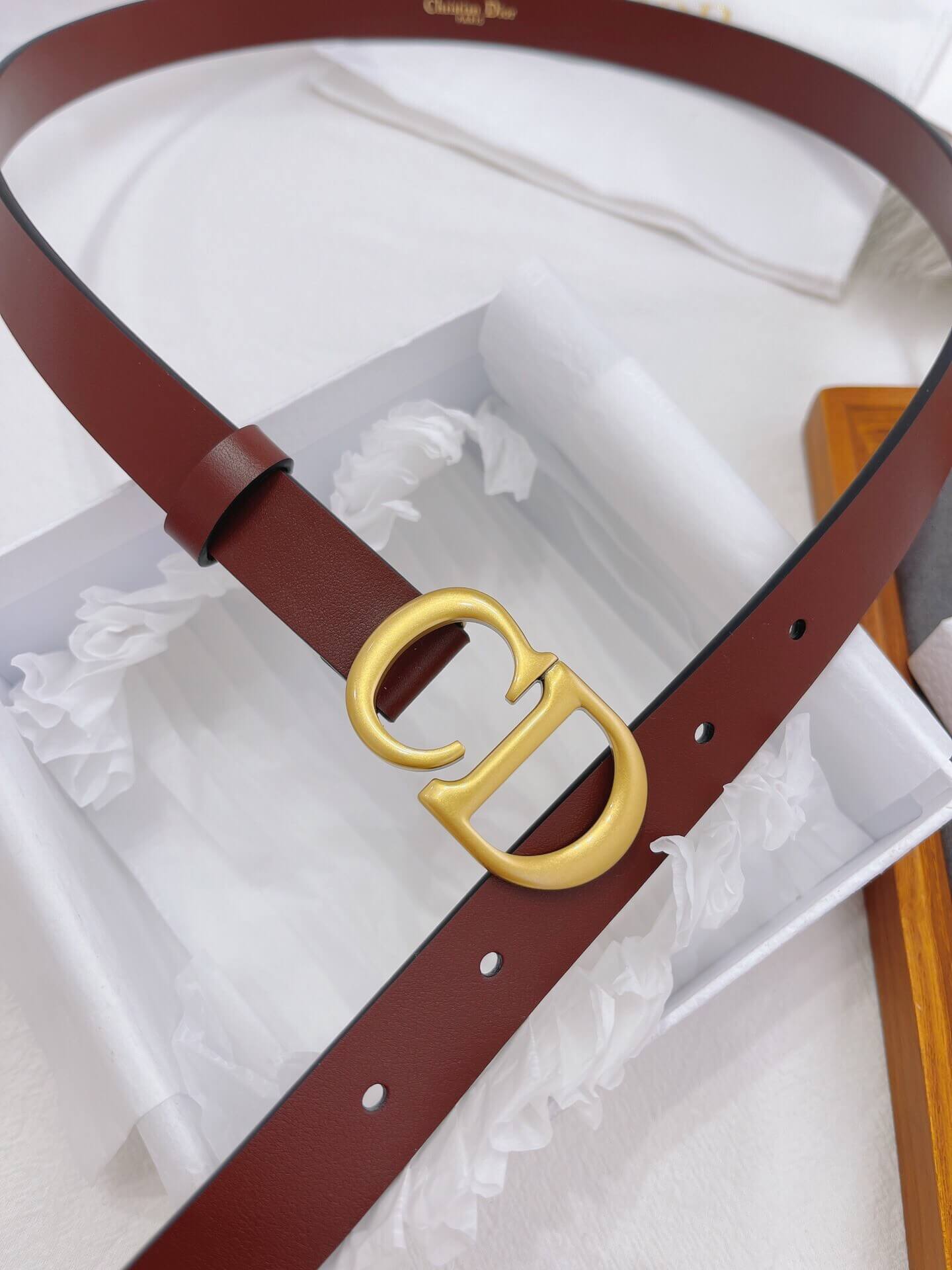 Brown belt with gold buckle in a white box