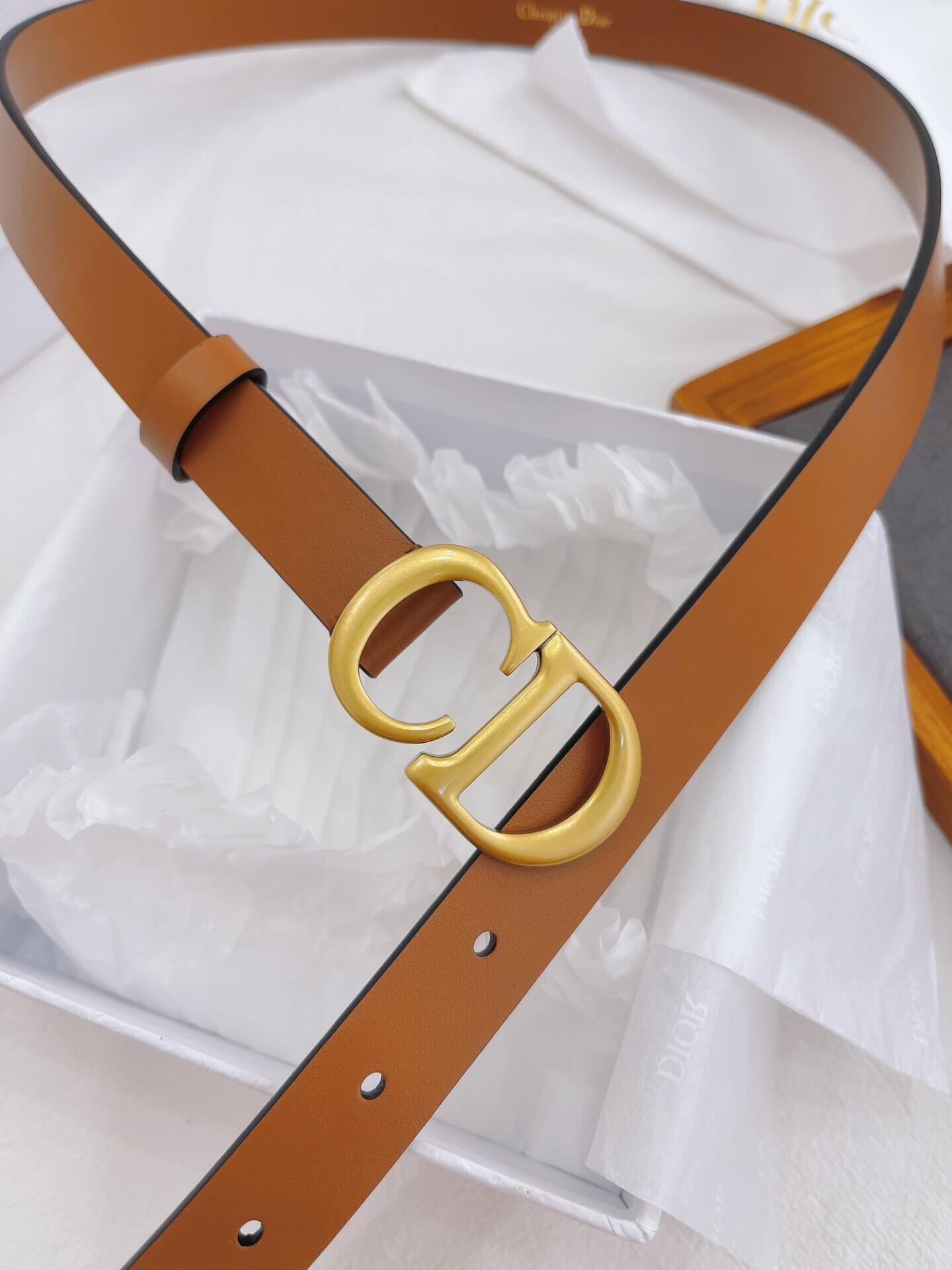 Brown belt with gold Dior buckle on a white background