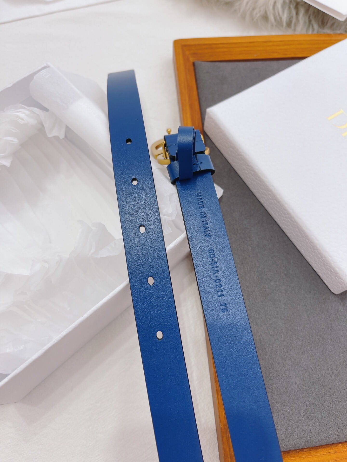 Blue belt with gold buckle on a white surface