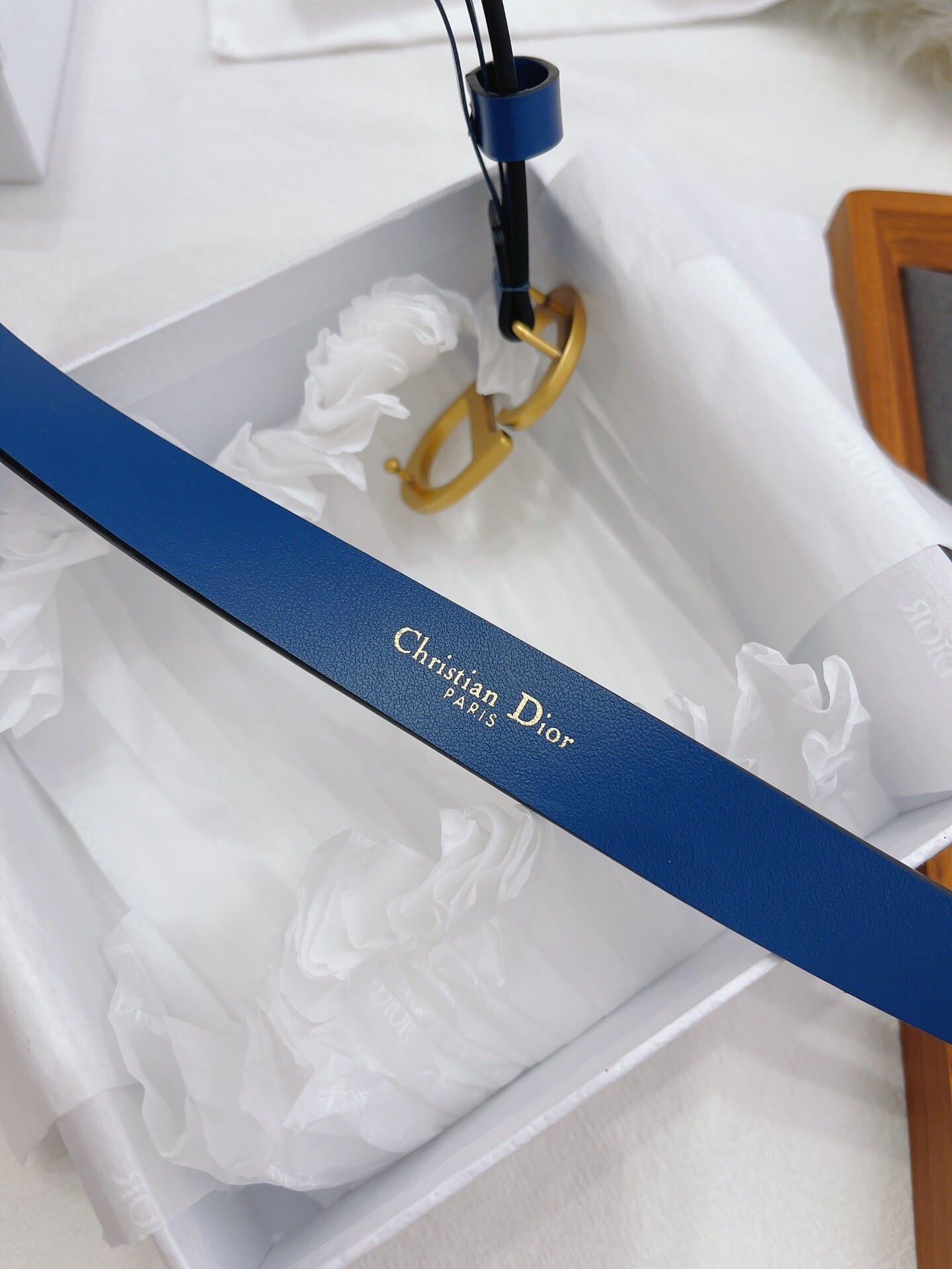 Blue belt with gold clasp and 'Christian Dior' branding on a white background