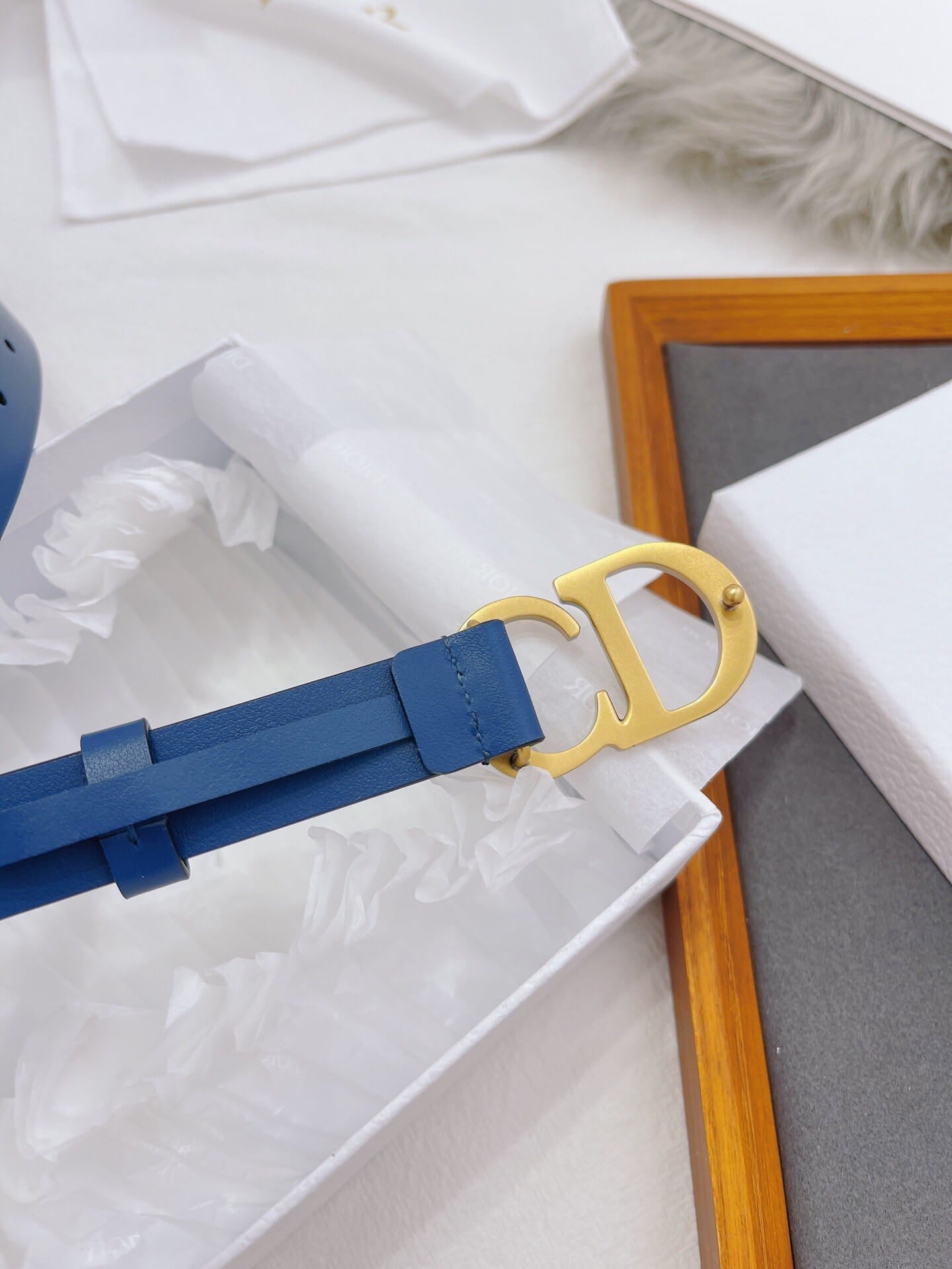 Blue belt with a gold buckle on a white surface