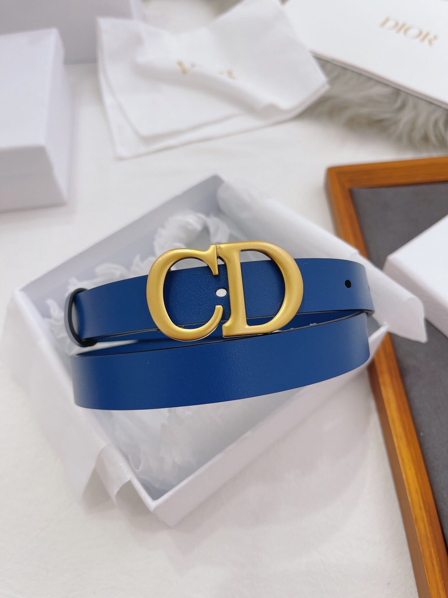 Blue belt with gold Dior buckle on a white background