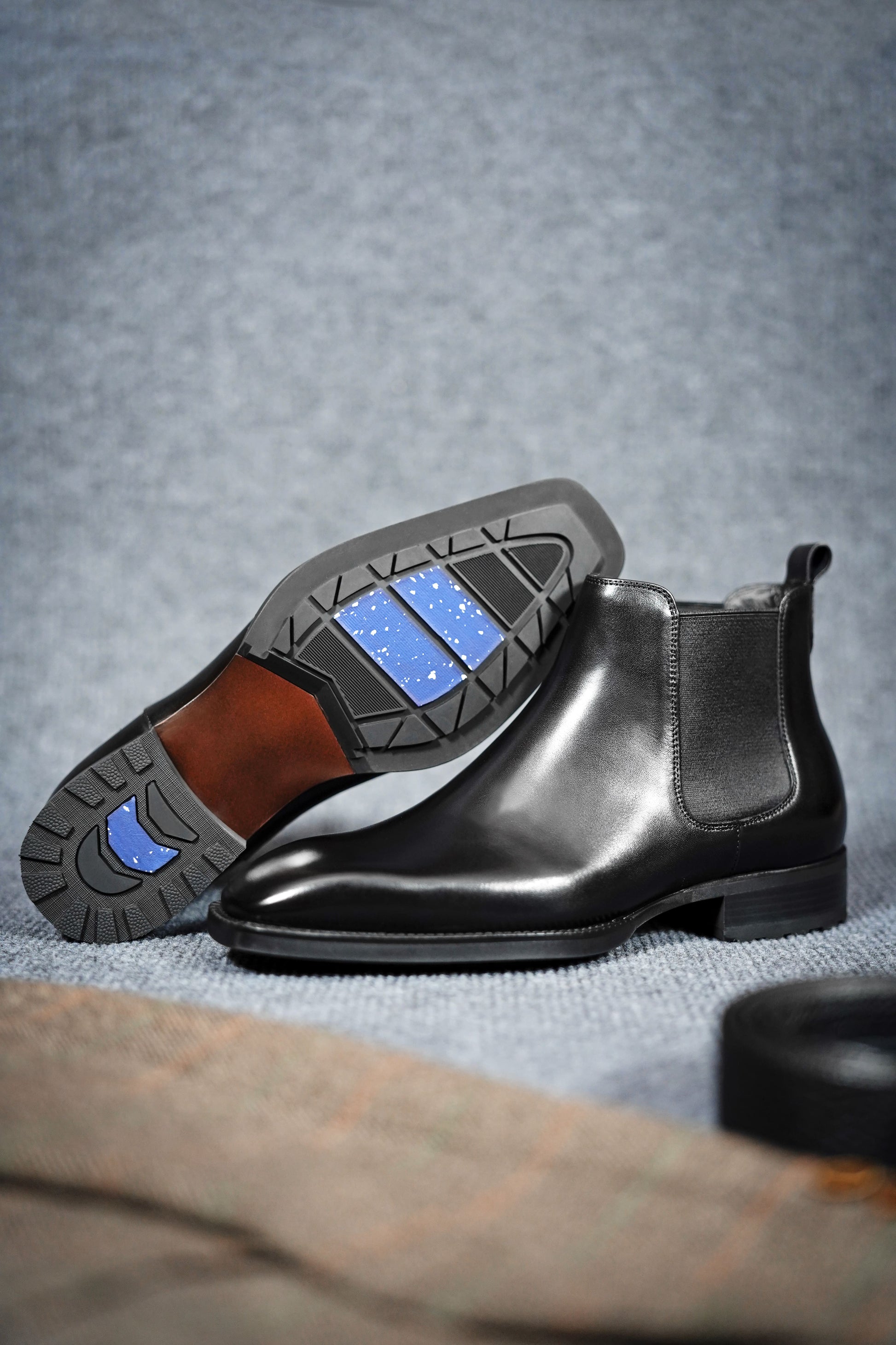 Classic Black Leather Chelsea Boots for Enduring Style – a pair of black leather boots on a gray background, with one boot turned to show the distinctive sole.