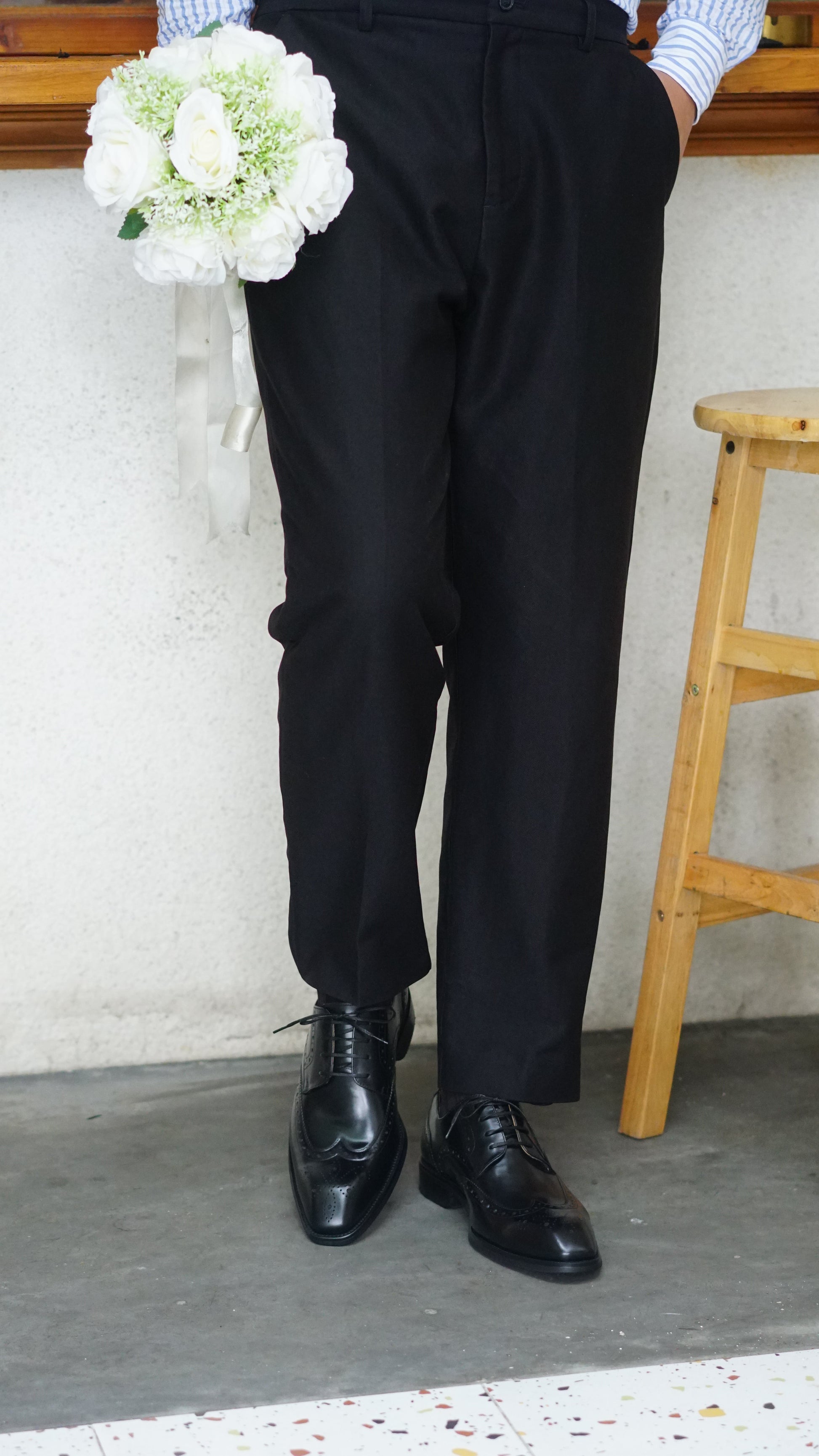 Men's Classic Black Wingtip Brogue Derby Shoes – close-up on feet, showing intricate brogue detailing and sleek black leather worn with black trousers.