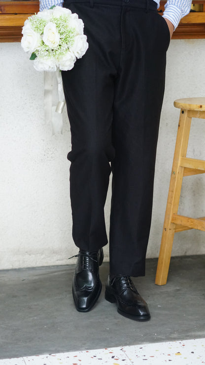 Men's Classic Black Wingtip Brogue Derby Shoes – close-up on feet, showing intricate brogue detailing and sleek black leather worn with black trousers.