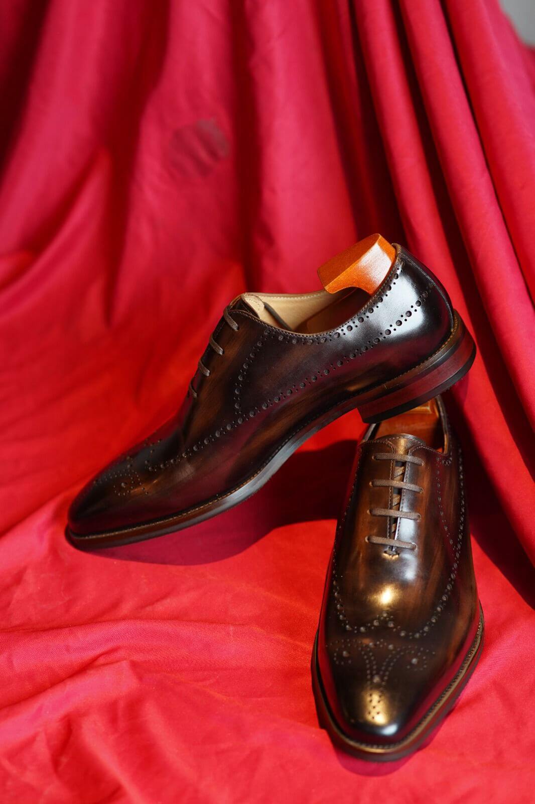 Pair of brown leather shoes on a red fabric background