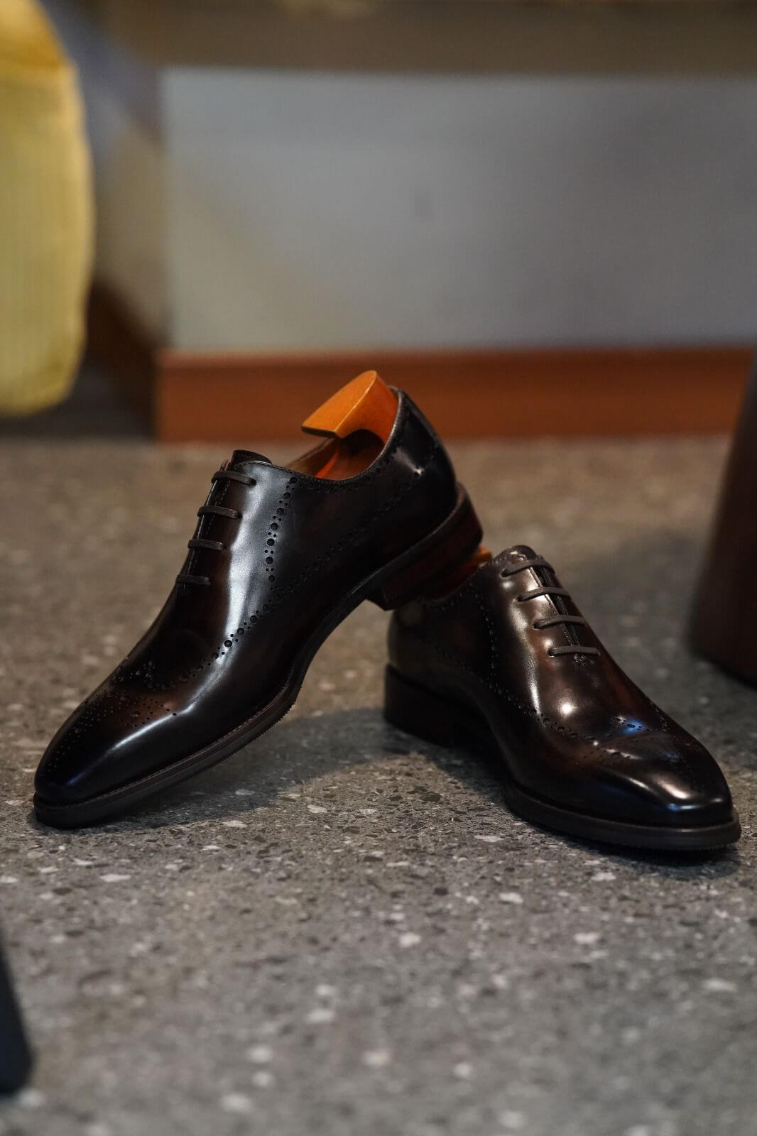 Pair of brown dress shoes on a textured surface with a blurred background