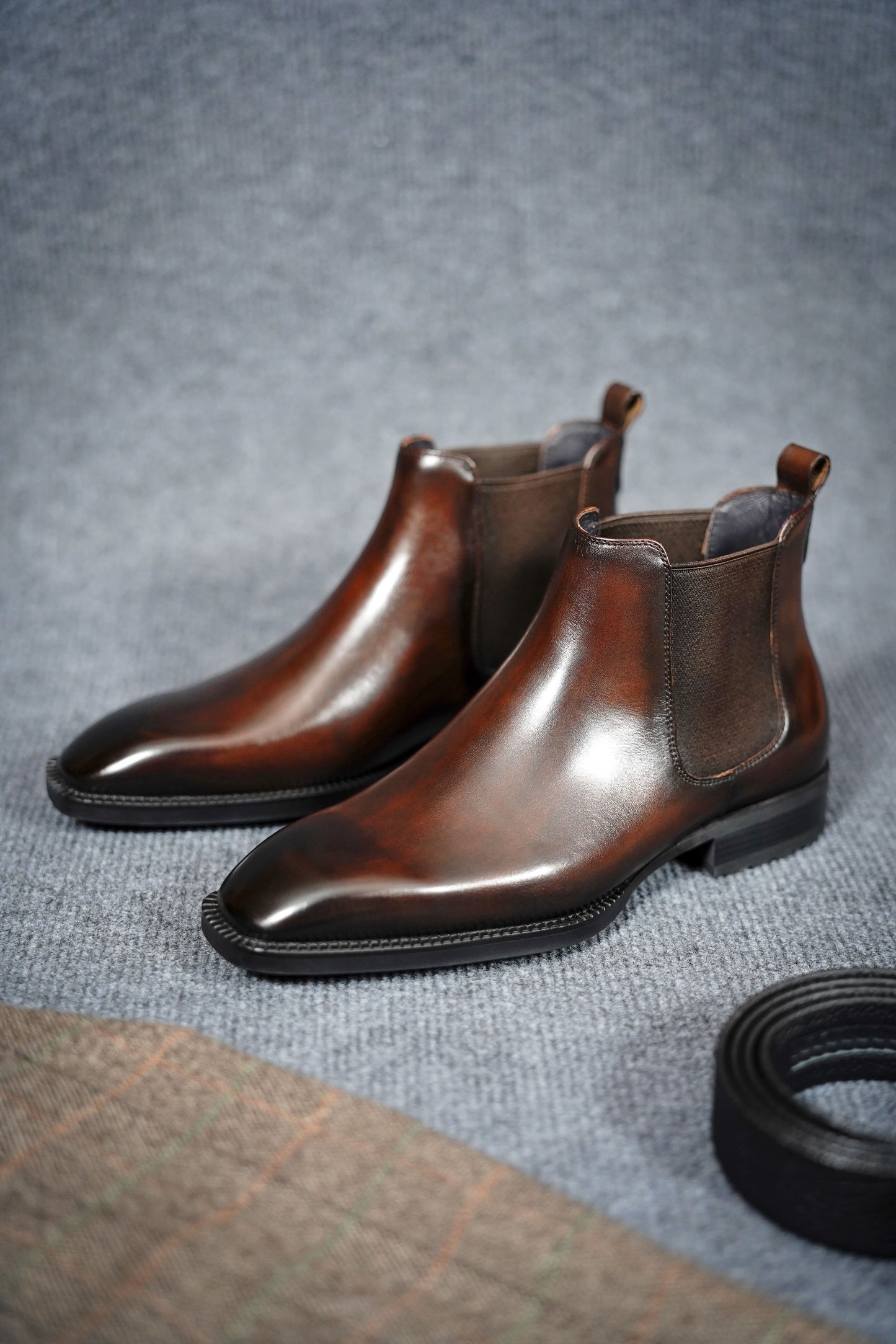 Classic Brown Leather Chelsea Boots for Everyday Versatility – a side view of the brown leather boots with a belt and checkered fabric, highlighting their elegance.