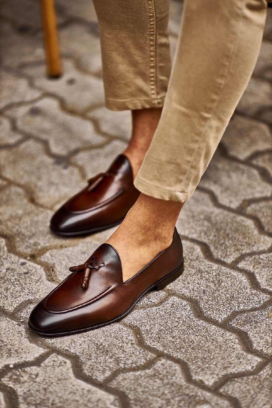 Brown Leather Tassel Loafers for Versatile Style – worn by a man in light cuffed trousers, sitting in a chair, showcasing timeless elegance and sophisticated style.