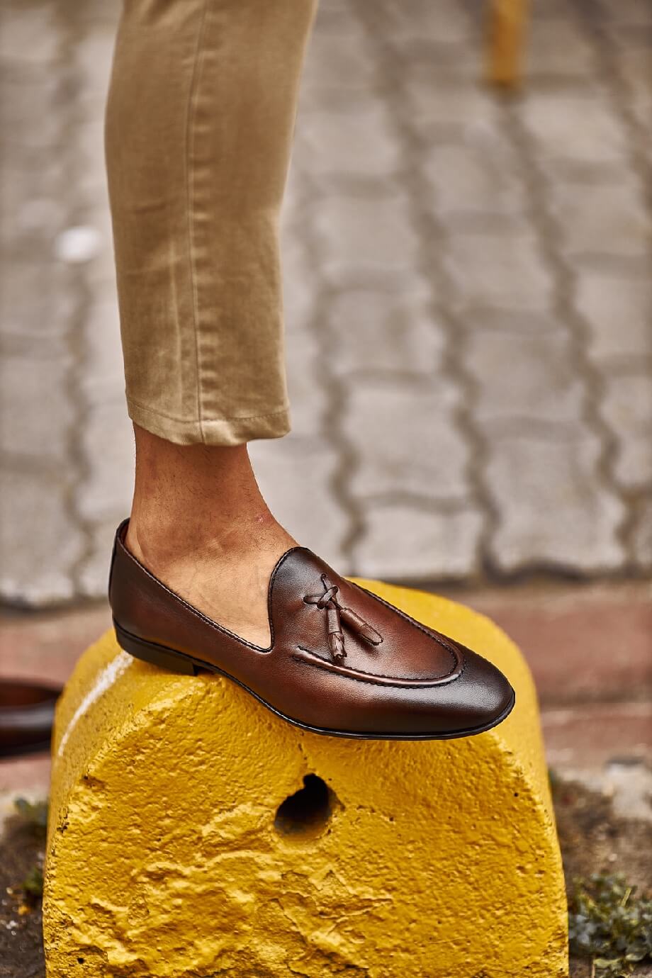 Classic Brown Leather Tassel Loafers for Versatile Style – worn by a man standing on a yellow concrete block, highlighting a refined design and brown color.