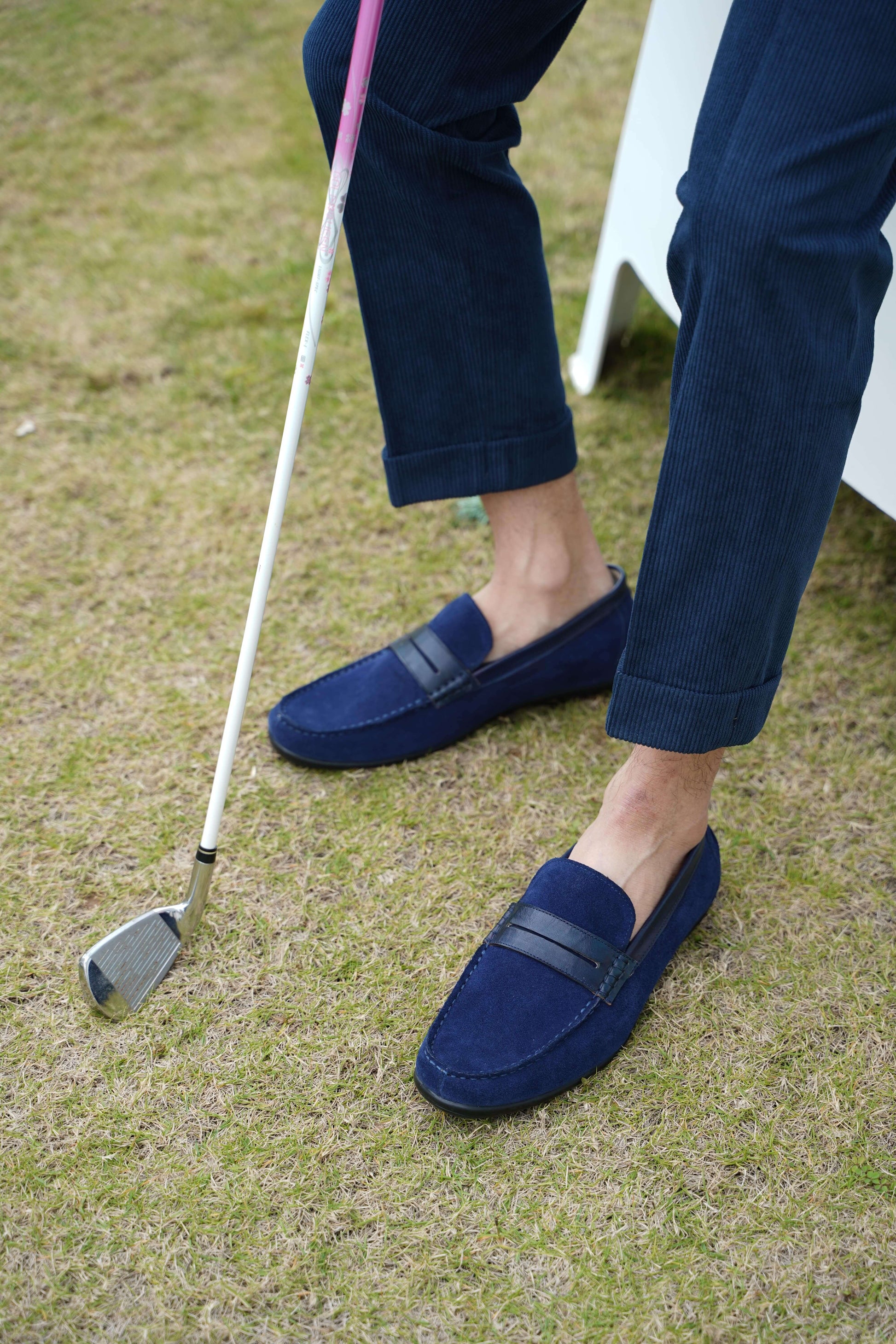 Classic Navy Blue Suede Driving Loafers – worn by a man in a denim shirt and navy trousers, holding a golf club, showcasing a classic and sophisticated look.